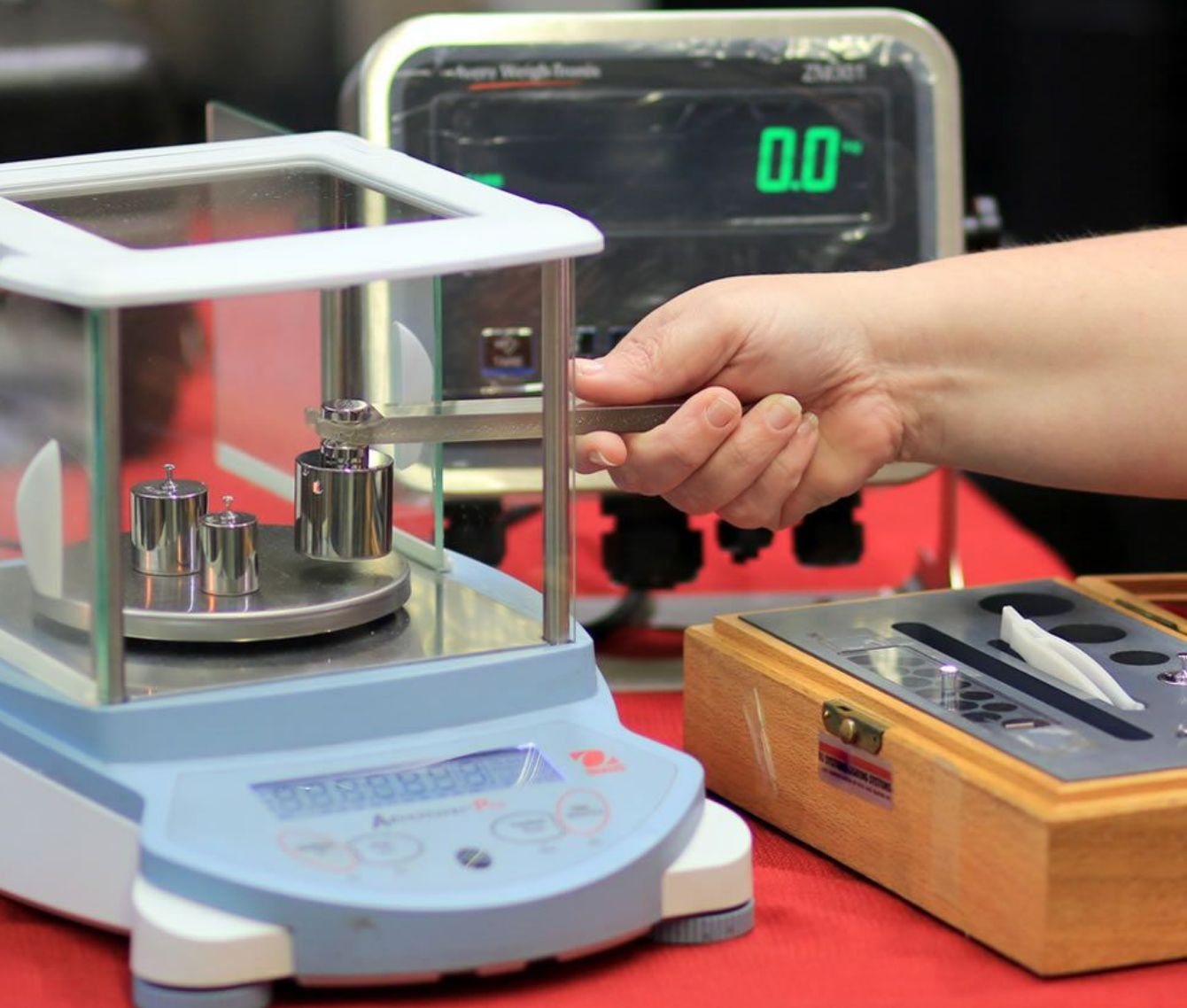 Technician placing a test weight on an analytical balance during calibration